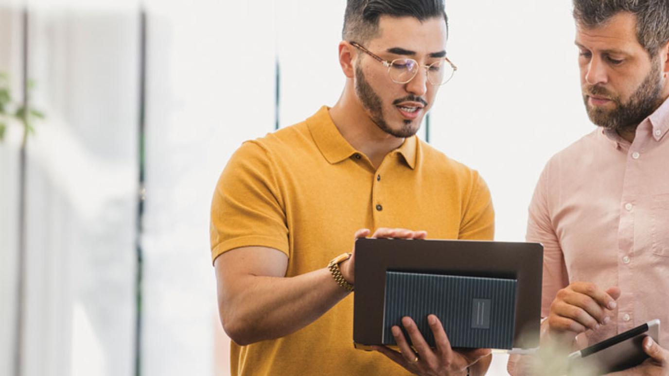 Two smart casually dress men reviewing plans on an ipad in an office setting