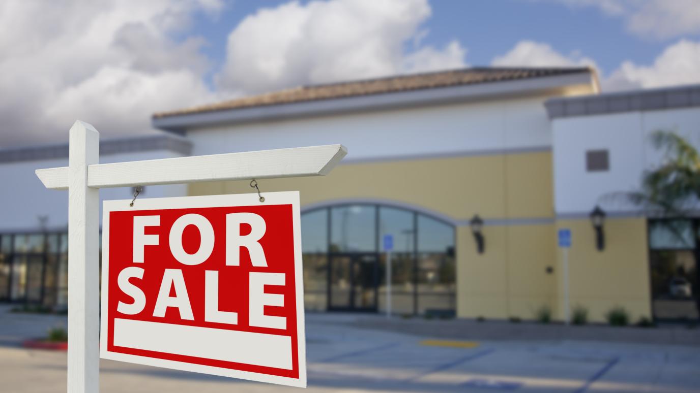 Commecial property in background with a for sale sign in foreground