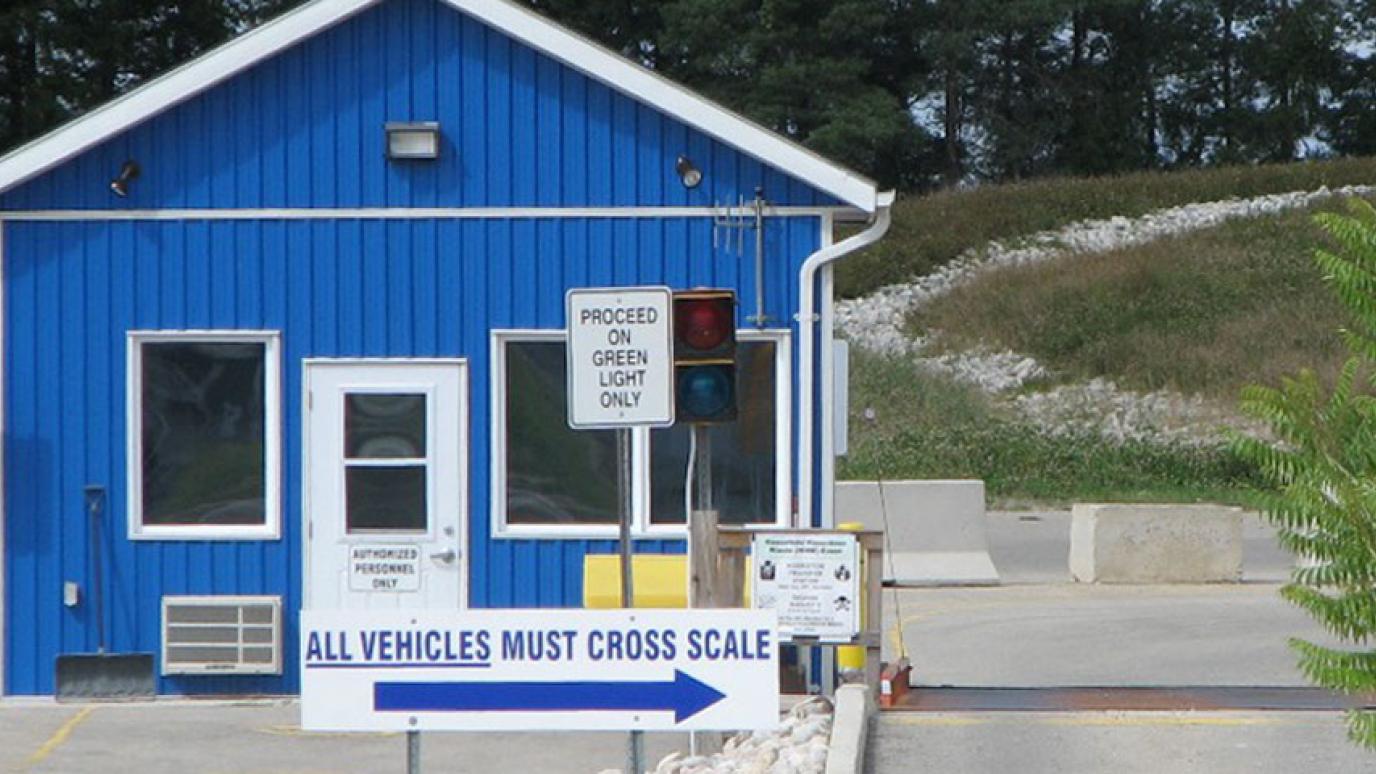 Small blue scalehouse at a waste facility with traffic signs direction vehicles onto the scales