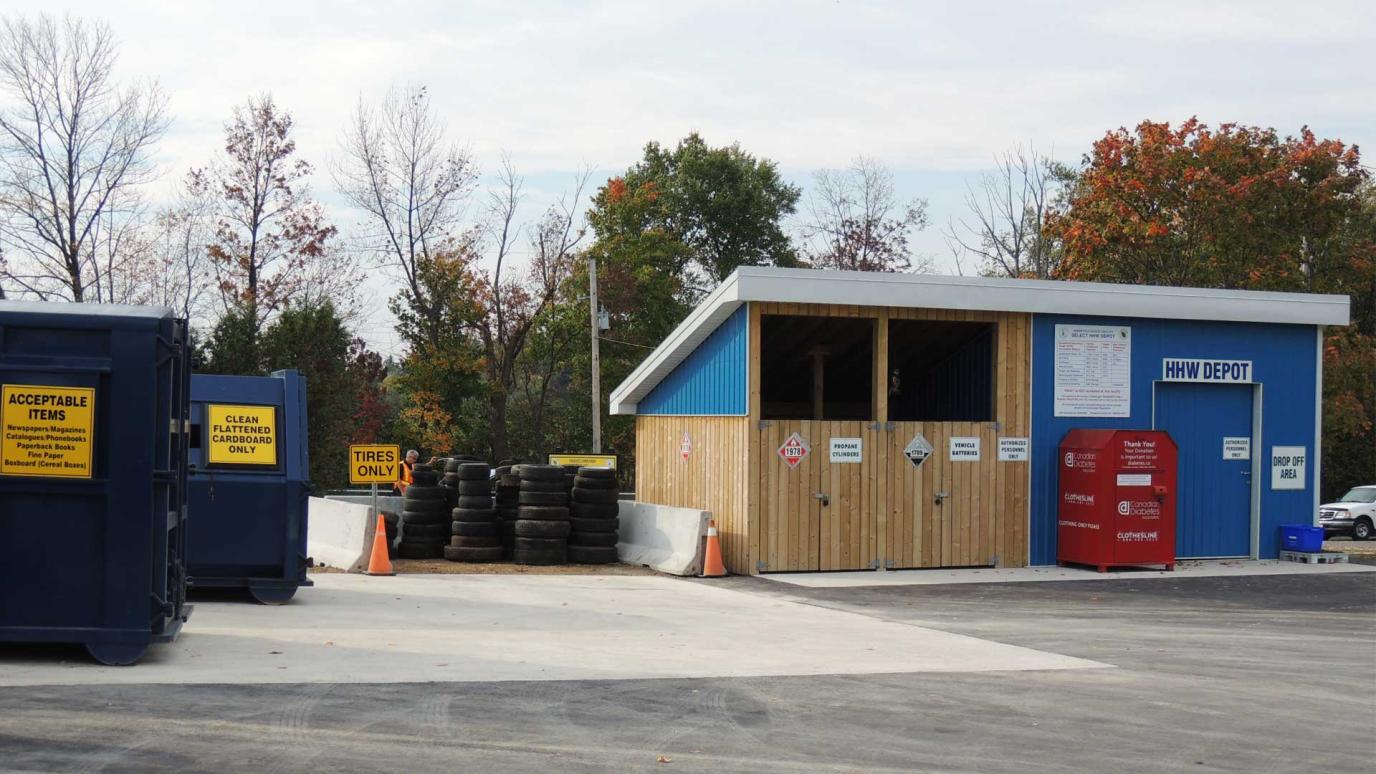 Waste Facility out building containing various waste items for collection next to large blue bins labelled with lists of their acceptable items