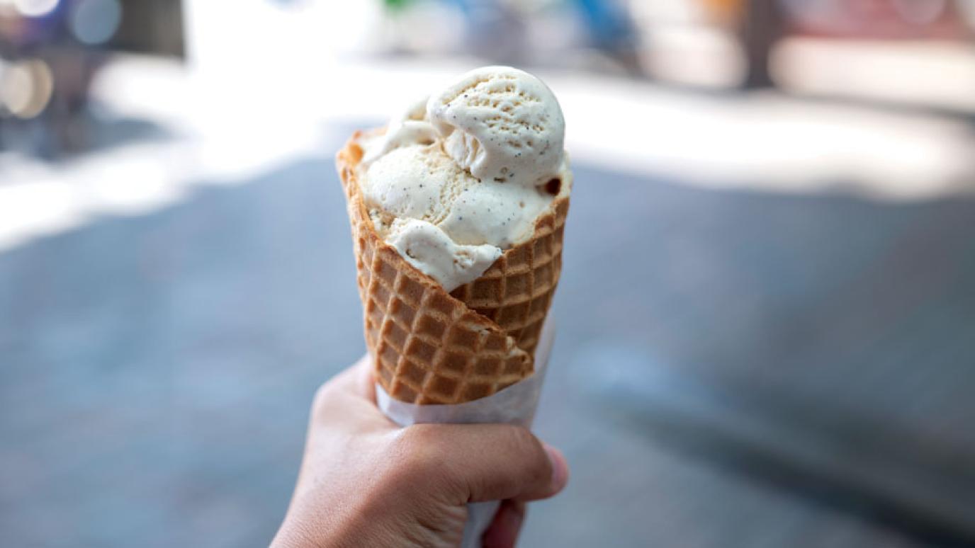 Hand holding a waffle cone with ice cream