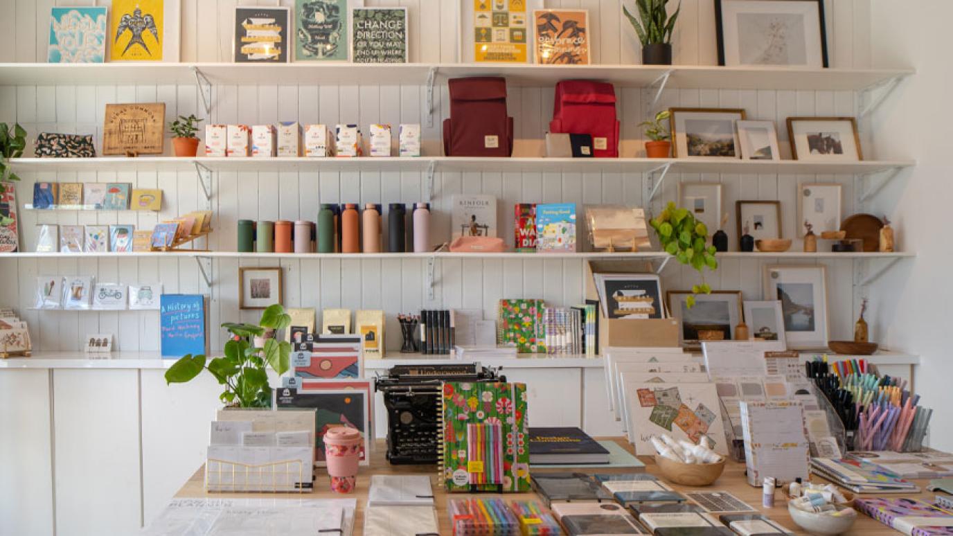 Colourful Art, stationary, journals and other products displayed cleanly on open shelves and table