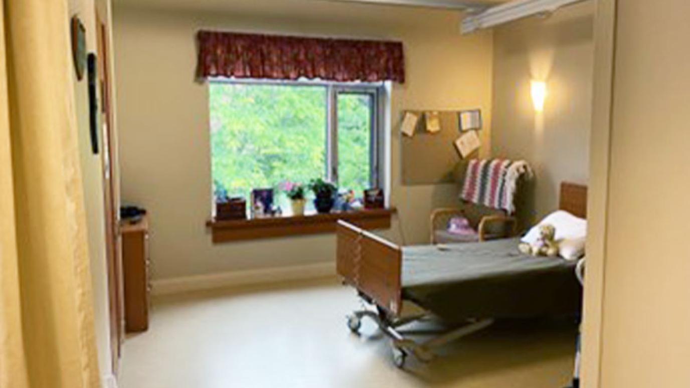 Basic Room, showing a residents room outfitted with a single bed, plants on the windowsill with a lovely garden view
