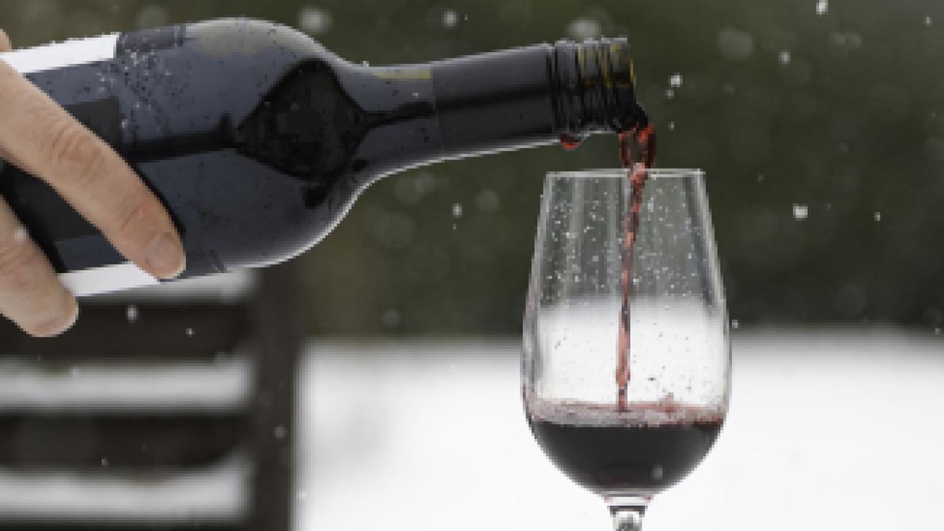 hand pouring red wine while snowing