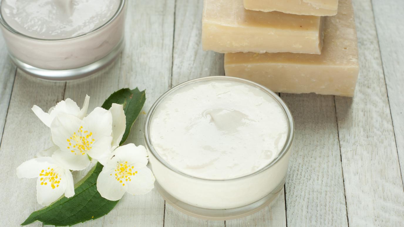 glass bowl of lotion and handmade soaps