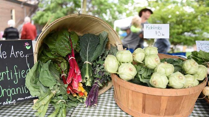 colourful swiss chard and kohlrabi sitting in baskets on a tabletop at a farmers market