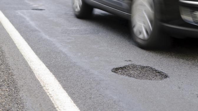 Car drives past a pothole.