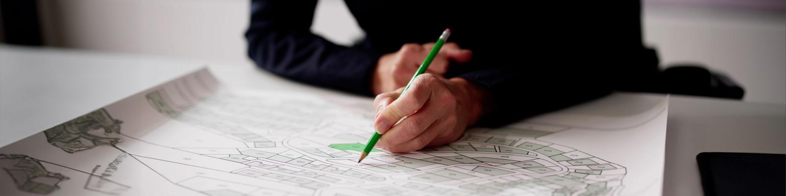 Womans hands drawing on a land plot map and building survey