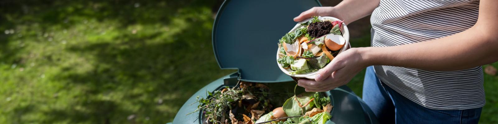Close Up Of Woman Emptying Food Waste Into Garden Composter At Home