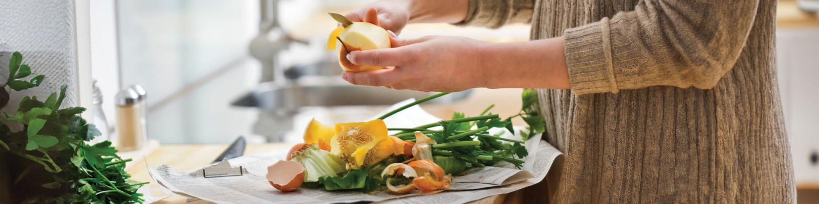 Crop of person in the kitchen peeling vegetables and collecting the waste scraps on newspaper to go in the green bin