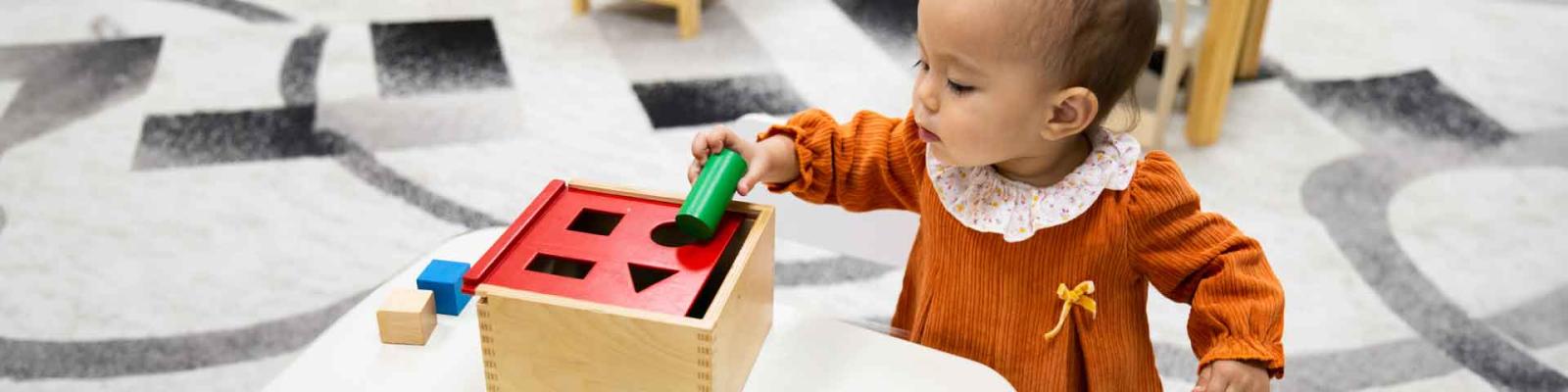 Young toddler matching wooden block shapes at daycare