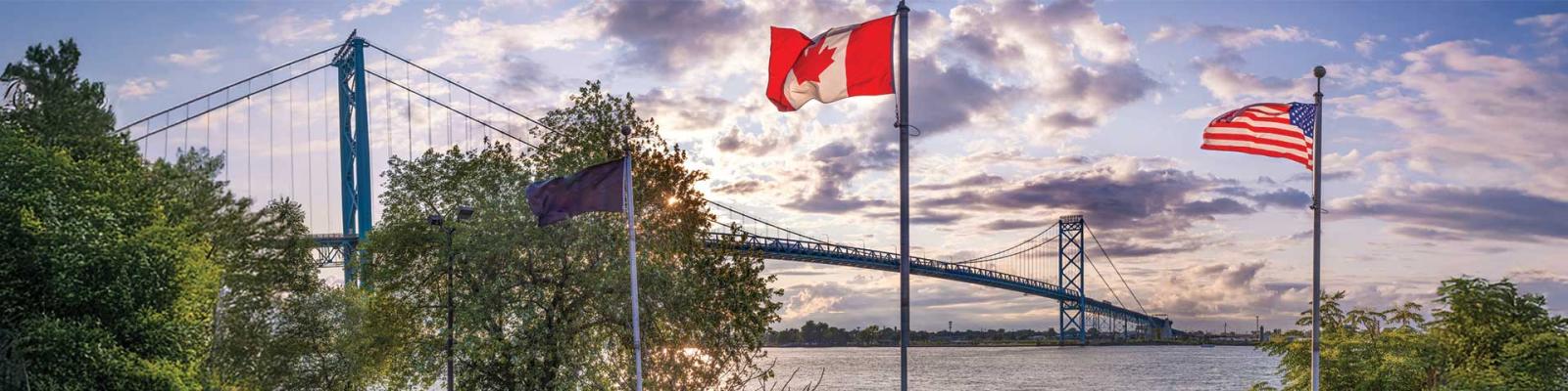 Photo overlooking the Ambassador Bridge where both the Canadian and American flags can be seen side by side, giving the impression of solidarity.