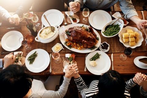 People gathered around a table of food with turkey