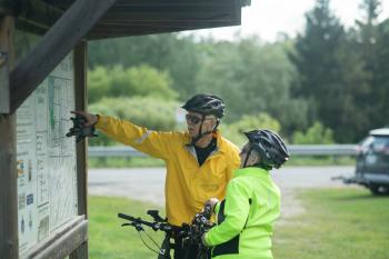 two cyclists looking at trail map outdoors