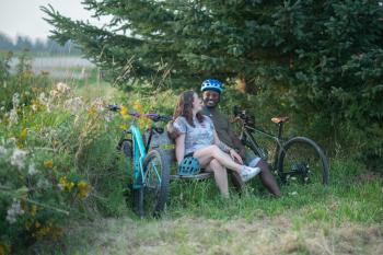 two people sitting on bench together with bikes leaning against the bench