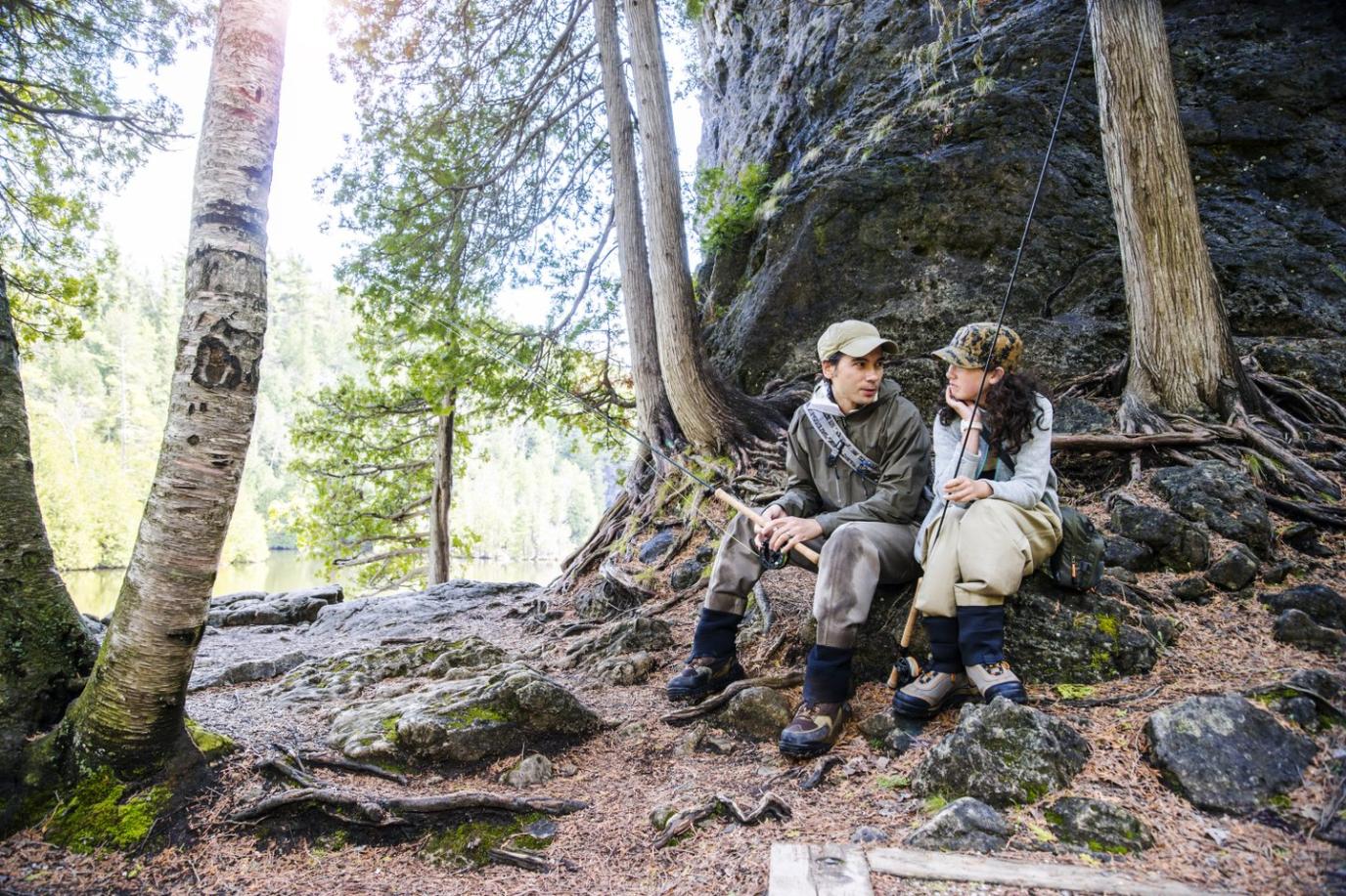 Two people sitting on a rock in a forest