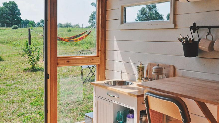 View from inside the farm stay cabin at BraeRidge Alpaca Farm and Santuary, shows brightly lit kitchenette looking out to a hammock outside