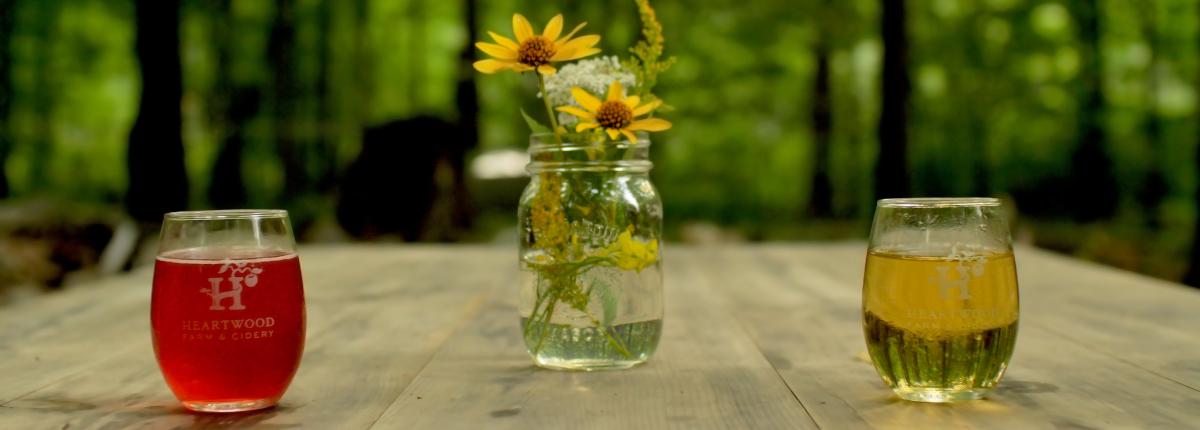 two glasses of cider on a table with flowers