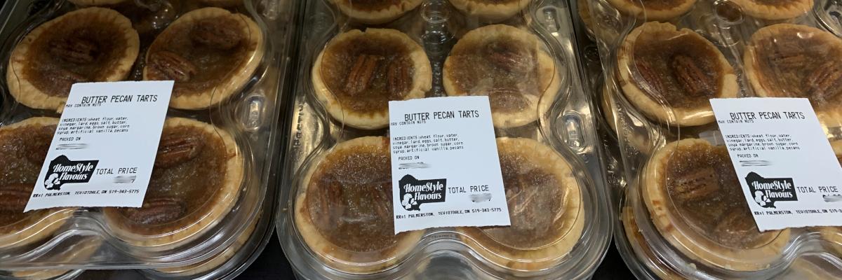 trays of butter tarts with white labels on them