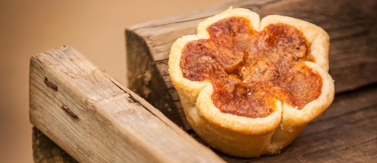 A flower-shaped butter tart rests on a rustic wooden surface.