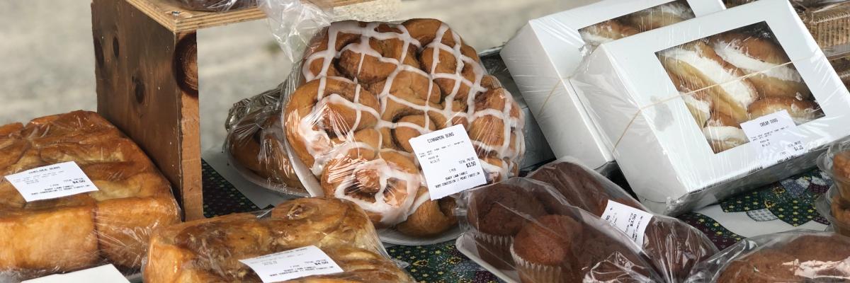 variety of fresh baked breads and pastries on display including a round lattice topped loaf and boxed treats
